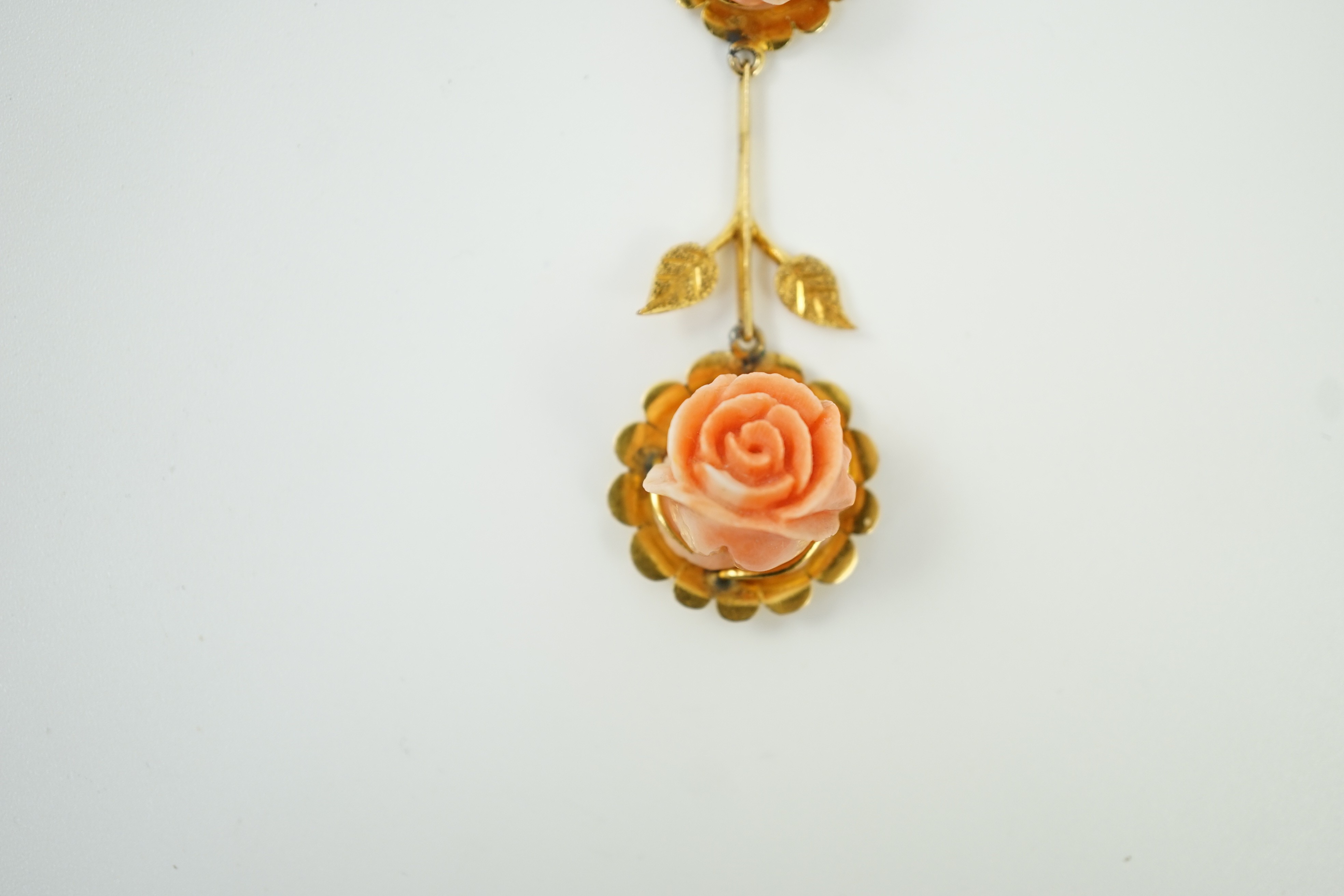 A yellow metal and two stone carved coral set 'rose' drop pendant, overall 57mm, gross weight 6 grams.